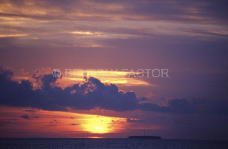 Islands;sunsets;sky;clouds;colorful;blue water;sun;yellow;red;pink;sillouettes;blue;maldive island